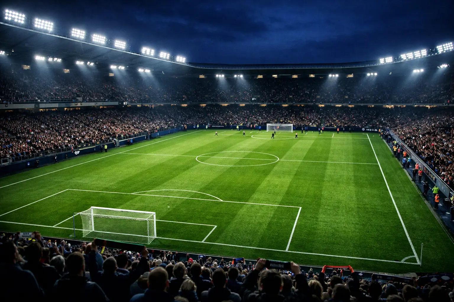 Stadio di calcio illuminato durante una partita serale con tifosi sugli spalti