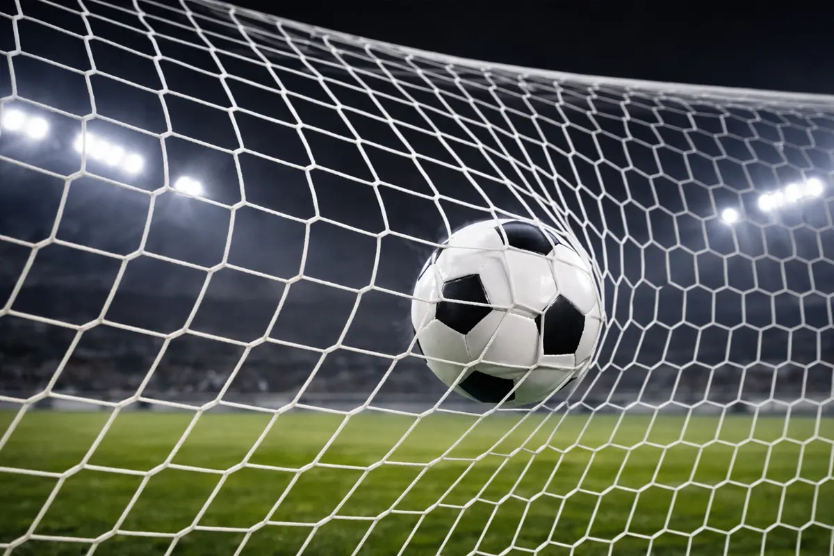 Rete da calcio vista da dietro la porta con il pallone che entra durante una partita serale sotto i riflettori